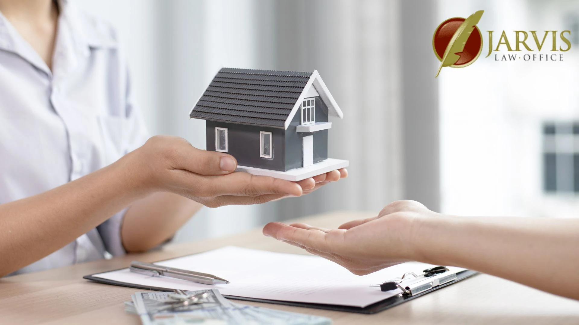 Person handing model house over desk