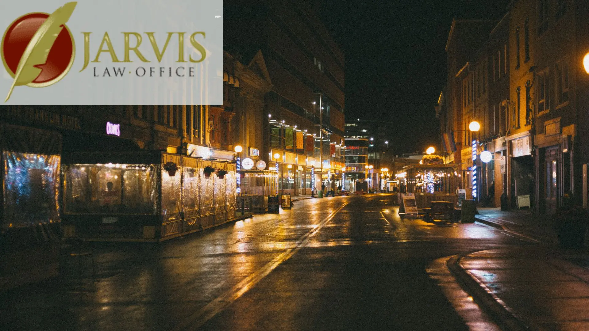 Wet downtown street at night with storefront lights
