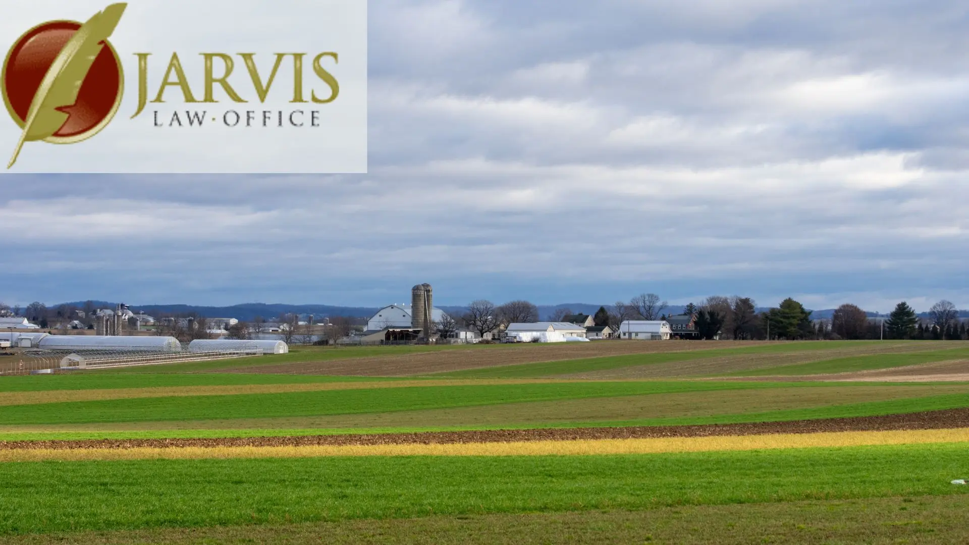 Rural farmland with barns and silos under cloudy sky