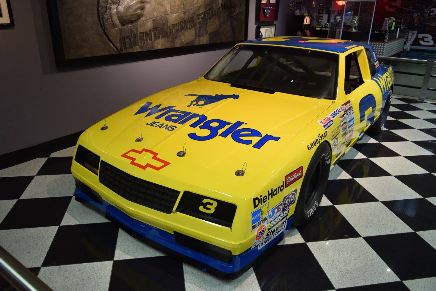 Yellow Wrangler race car on checkered floor.