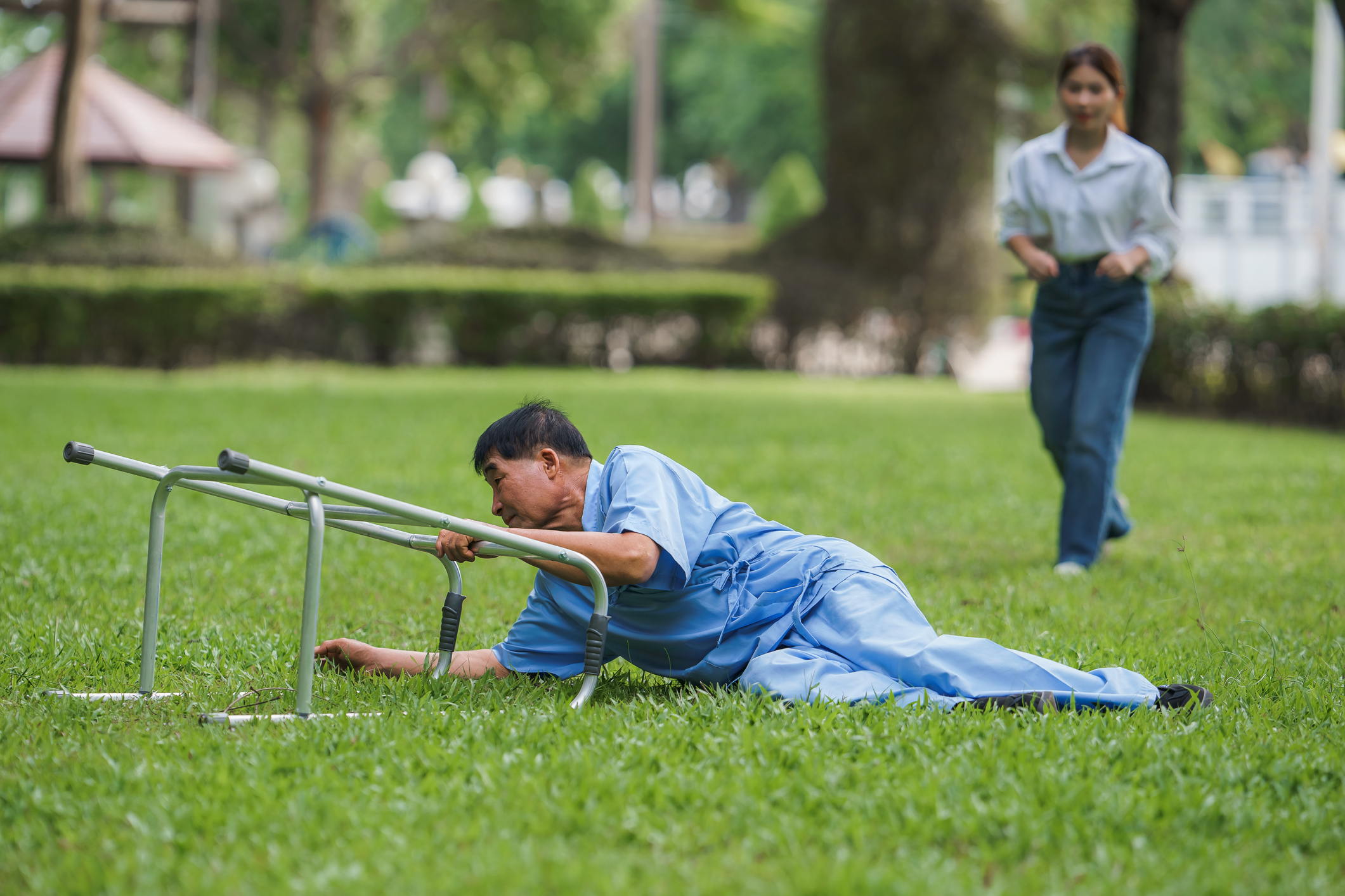 Elderly man falls on grass using walker