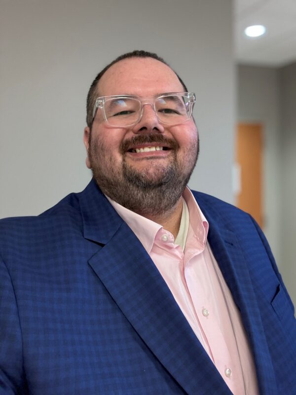 Smiling man in blue suit and pink shirt