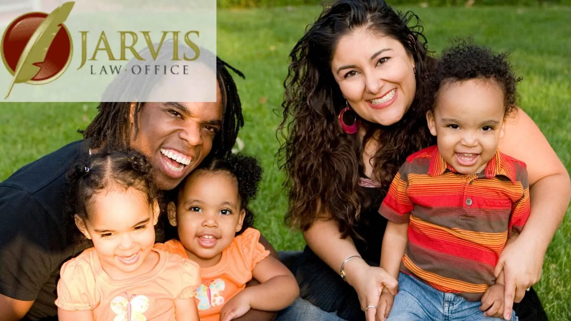 Smiling family of five sitting on grass outdoors