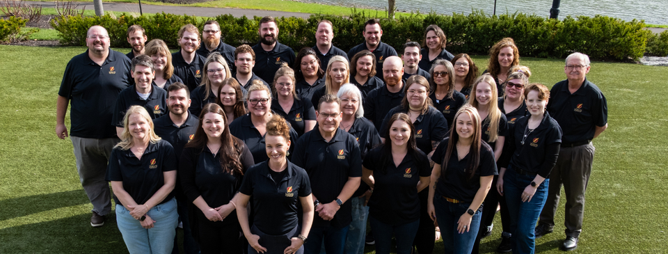 Large staff group in black polos outdoors